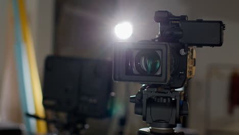 Close-Up-Of-Film-Or-Video-Camera-On-Tripod-Shooting-Movie-Or-Video-In-Studio